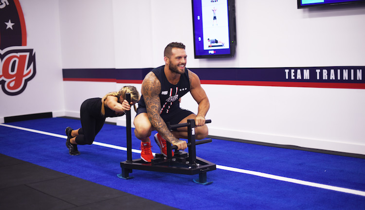 woman pushing weight sled with man sitting on it