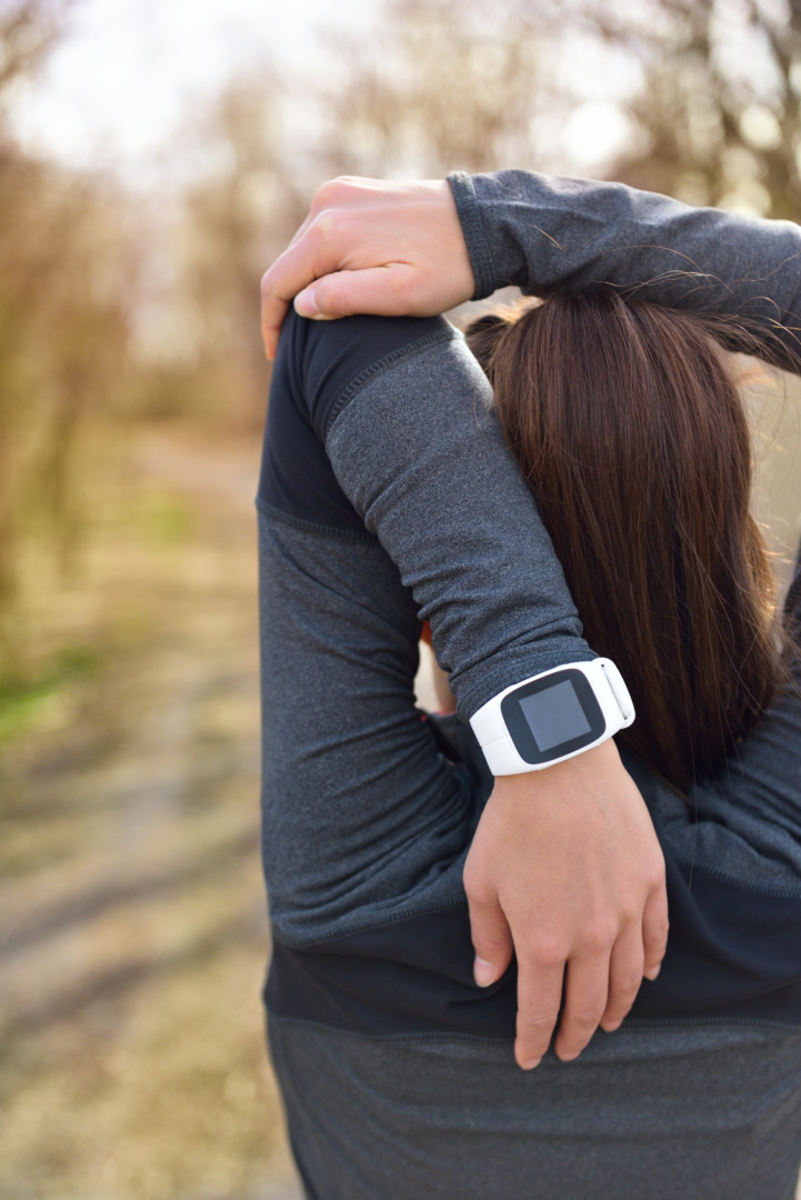 runner stretching wearing her fitbit watch