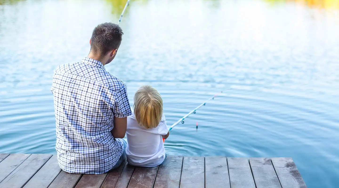 father and sun fishing off a dock