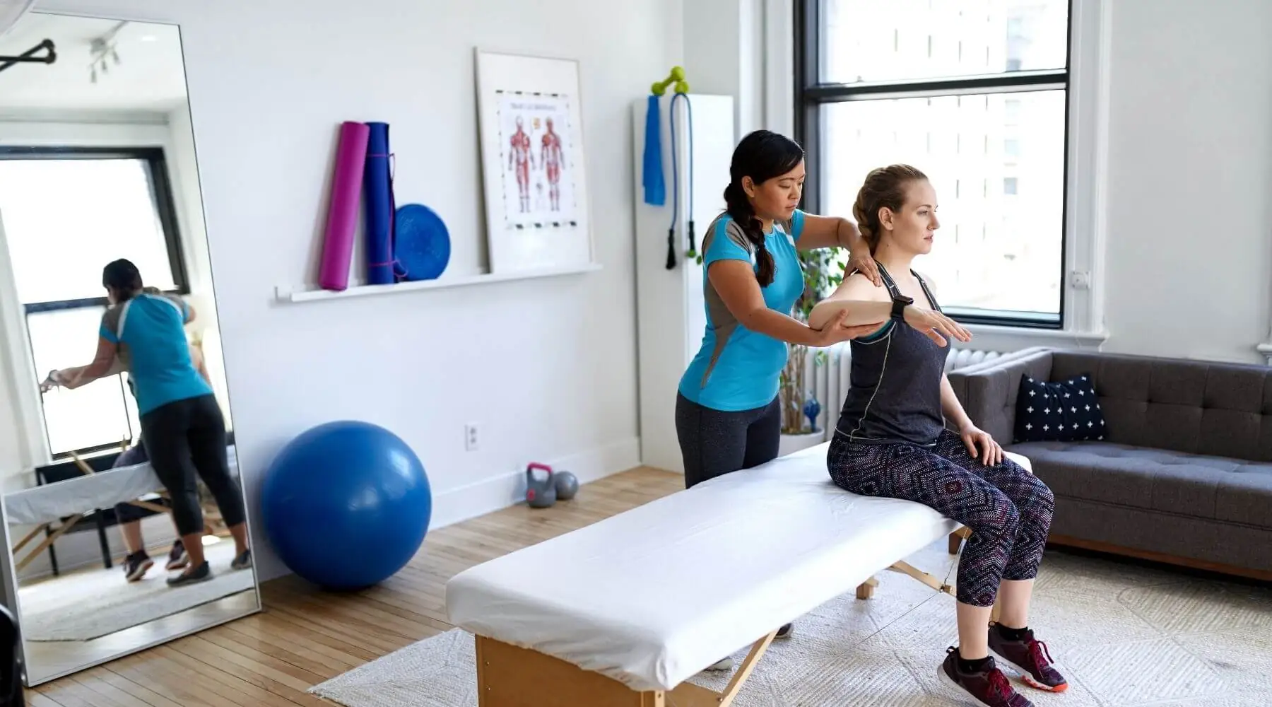 Female PT holds arm of patient in bright white room