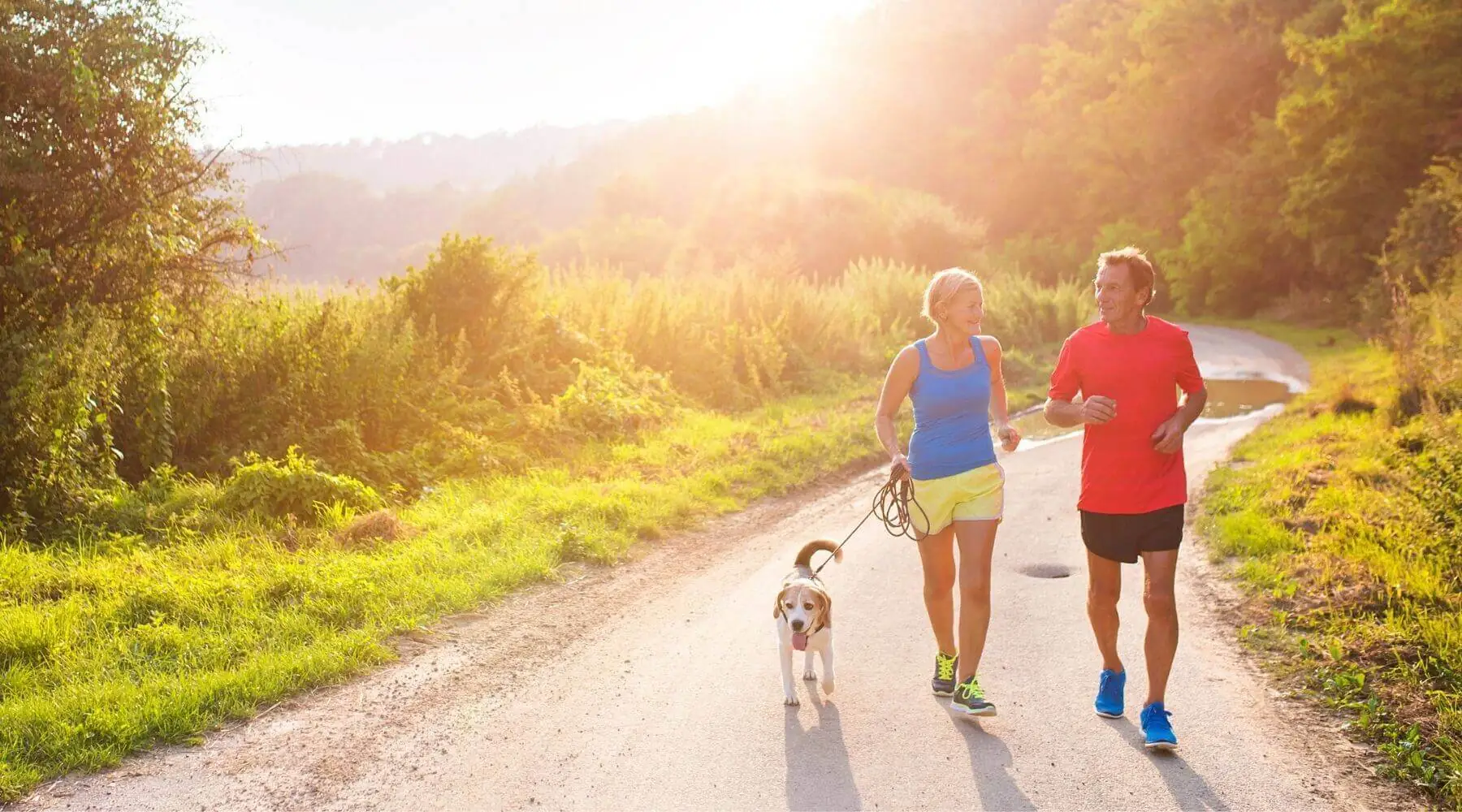 Older Couple running with dog in sunlight
