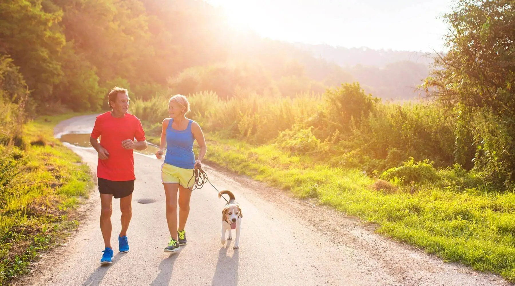 Older Couple running with dog in sunlight