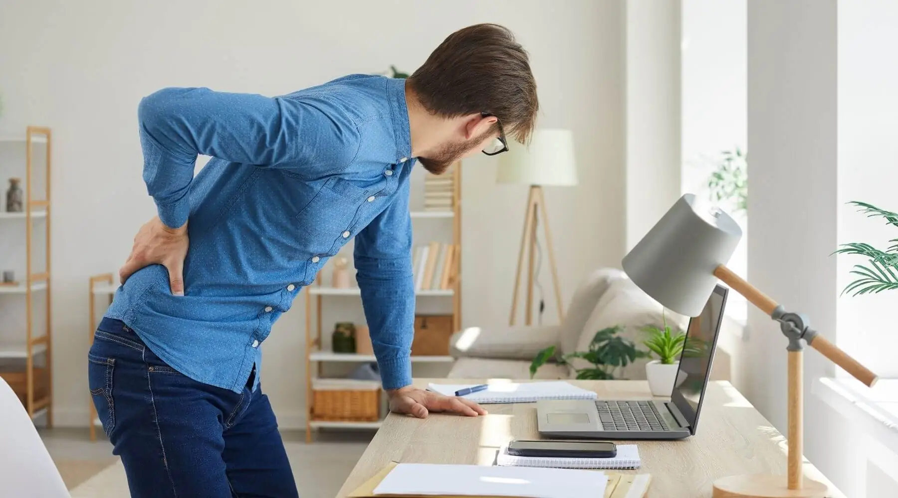 main with back pain bent over desk